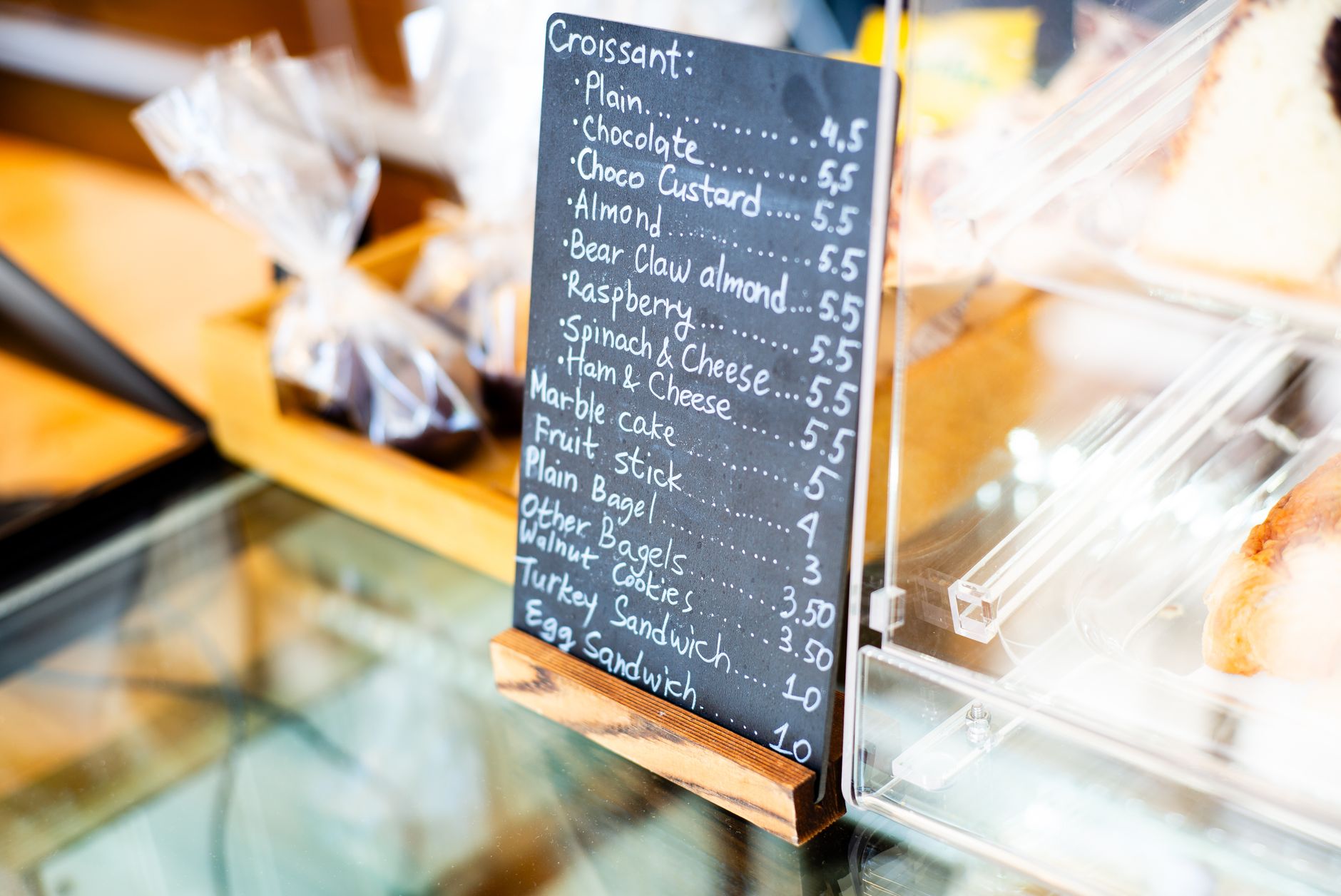 Interior of a warm, rustic cafe featuring a large empty chalkboard menu above the counter, ready to be filled with creative cafe names and drinks.