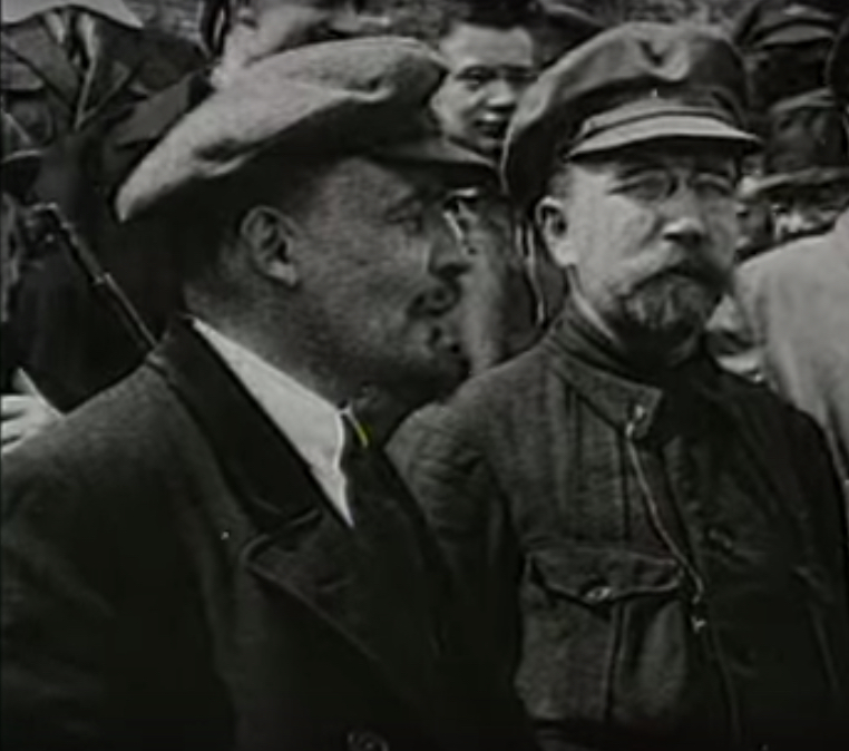 Interior of an old Soviet-style movie theater with a Lenin-themed film playing on the screen as an audience watches