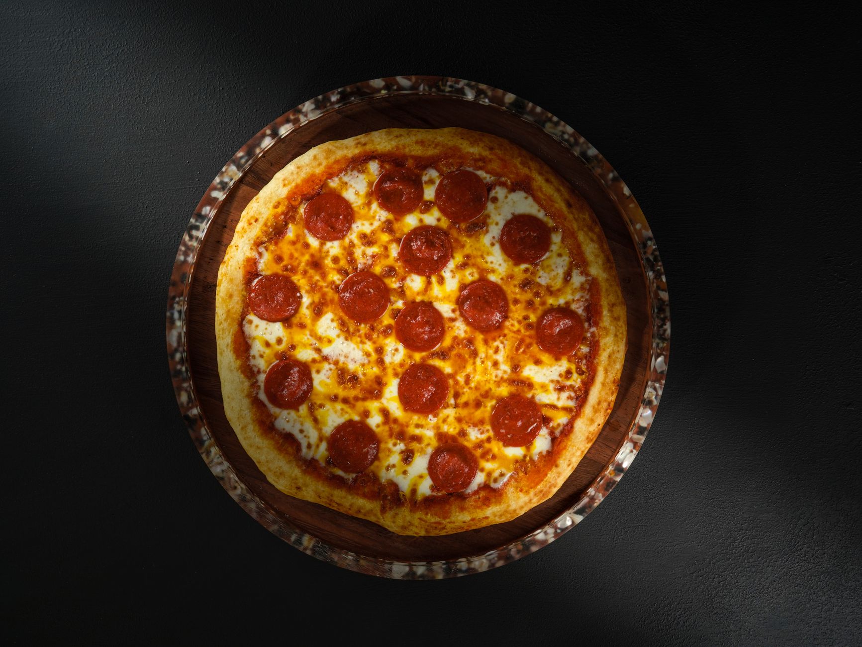 Overhead close-up of a pepperoni pizza with one slice being lifted, used to illustrate a quiz-style article titled 